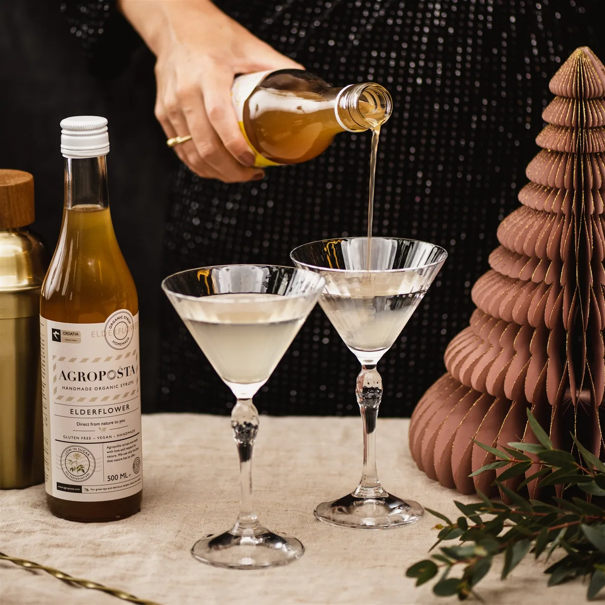 Agropošta elderflower syrup being poured into martini glasses